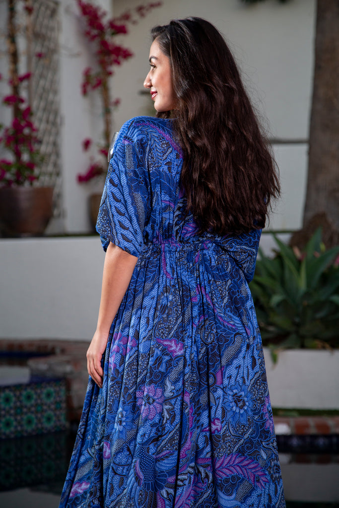 Back of a woman wearing Amy Kimono Dress in Batik Deep Royal Blue while holding a glass of wine