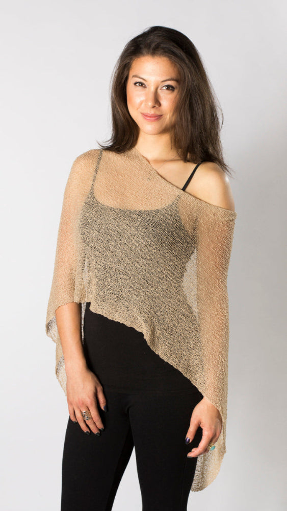 women in beige sheer shoulder ocver poncho over black outfit white background
