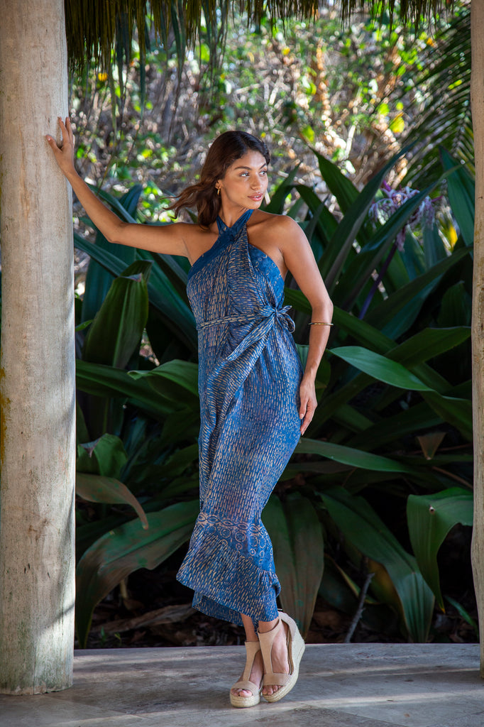 Woman standing wearing Brianna Wrap Skirt with Ruffled Edge in Denim Raindrop (Worn as a dress) in front of a forest.
