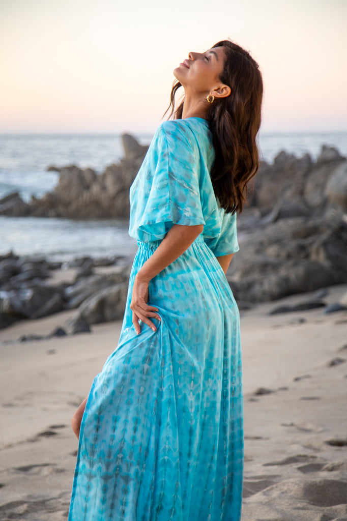 Side of a Woman wearing a Amy Kimono Dress in Premium Sophia Loren Turquoise Watercolor on a beach