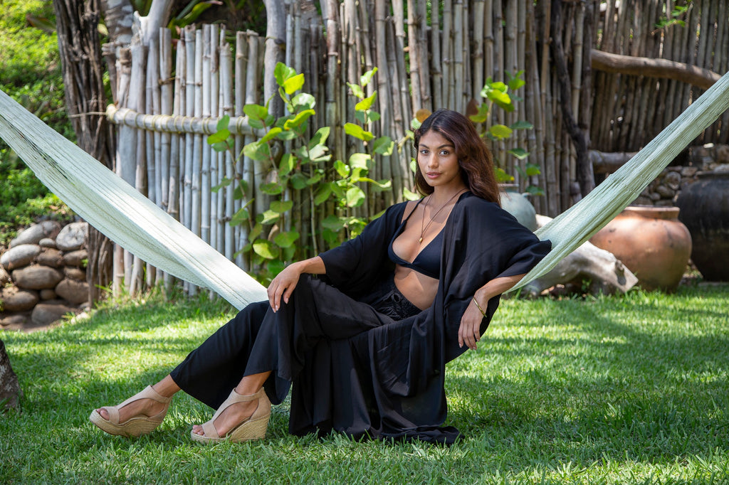 Front of a woman wearing Kaftan Robe and Pant set in Solid Black Premium on a garden.