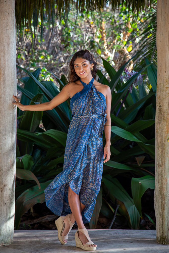 Front of a Woman standing wearing Brianna Wrap Skirt with Ruffled Edge in Denim Raindrop (Worn as a dress) in front of a forest.