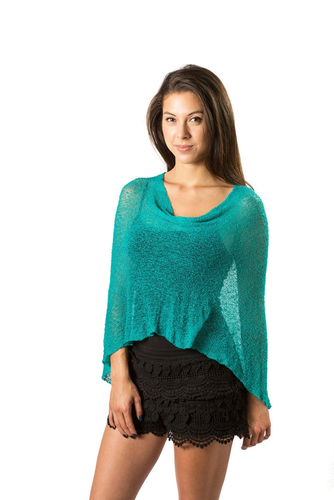 Woman standing upclose wearing Turquoise Teal Green Knit Poncho sweater shawl over black outfit white background