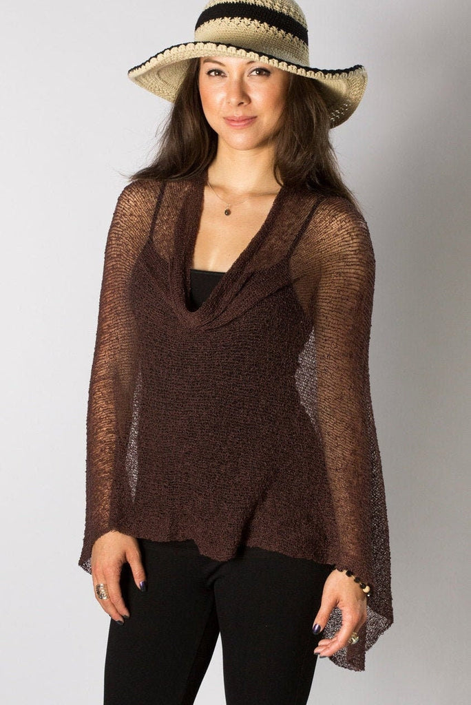 Woman standing upclose wearing Espresso Knit Travel Boho Poncho Shawl over black outfit and hat and white background